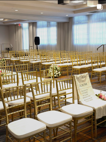 Rows of gold chiavari chairs set up for a wedding ceremony in a Daytona Beach ballroom.